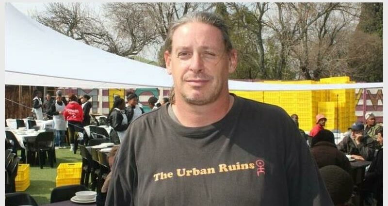 A white man with a black t-shirt written urban ruins.