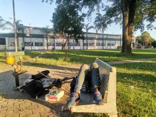 A homeless man sleeping on a park bench.
