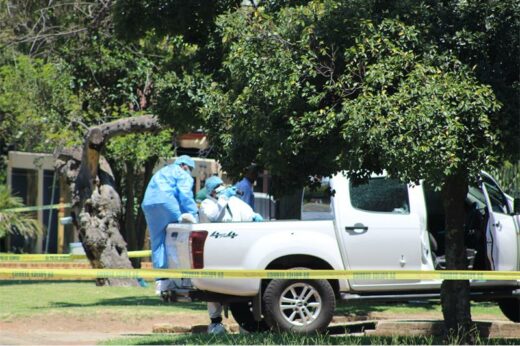 A white Isuzu bakkie riddled with bullet holes stands in a driveway of a residential area
