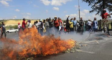 protesters blockade road with rocks and burning objects