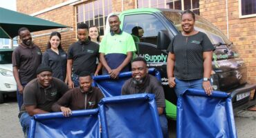 A group of workers from a factory standing in front of a vehicle with dog beds they have donated to the SPCA.
