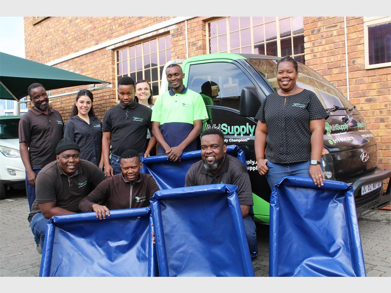 A group of workers from a factory standing in front of a vehicle with dog beds they have donated to the SPCA.