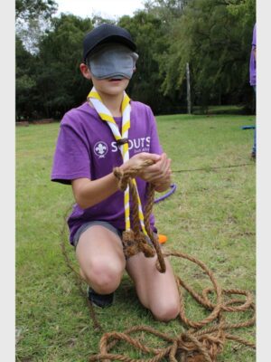 a young boy in a purple t-shirt and holding a rope