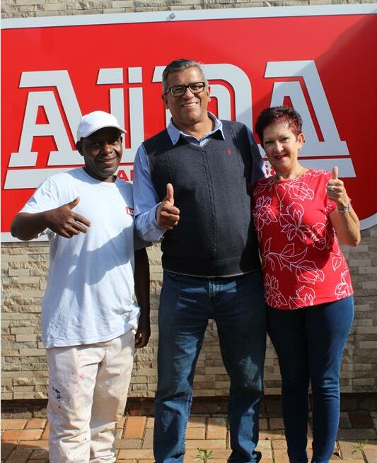 Two men and a woman posing for a photo with a company logo in the background