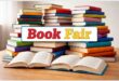 Books stacked on a table with the wording Book Fair.