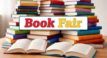 Books stacked on a table with the wording Book Fair.