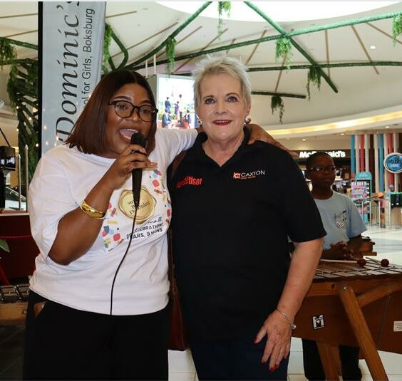 Two women one wearing a white top and the other in a black Boksburg Advertiser branded golf t-shirt