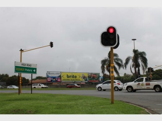 An intersection showing traffic lights and vehicles with grass in the forefront.