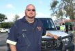 a male community rescuer standing next to his service vehicle