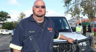 a male community rescuer standing next to his service vehicle
