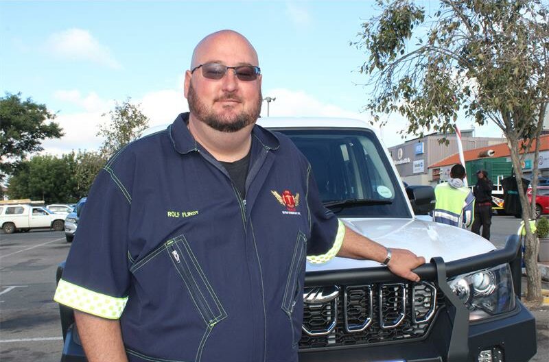 a male community rescuer standing next to his service vehicle