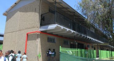 A two-storey school building with children playing outside.