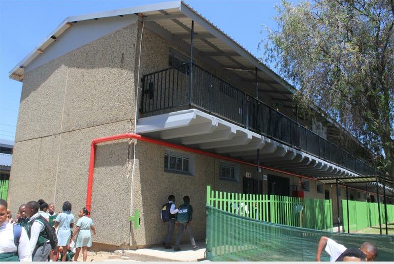 A two-storey school building with children playing outside.