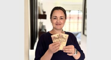 A woman in a black top holding R40 in cash