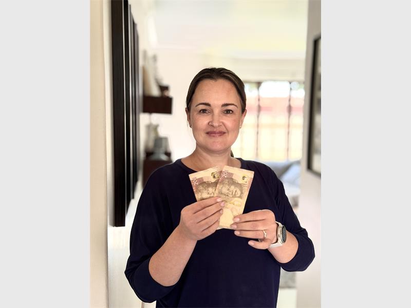 A woman in a black top holding R40 in cash