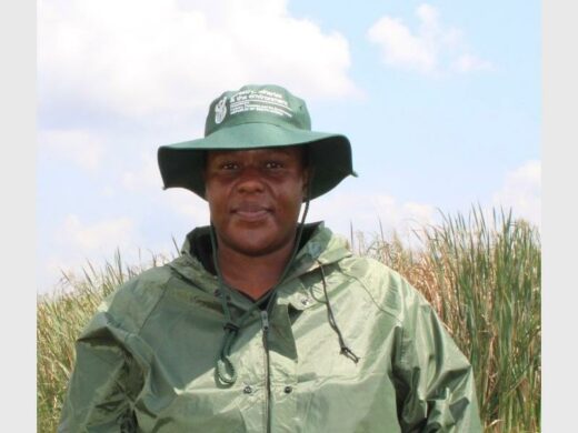 A black male wearing a khaki green anorak and a dark green hat. 