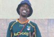 A black male smiling and wearing a Springbok shirt, a black bucket hat and giving a peace sign.