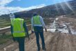 Two workers , a man and a woman in reflective safety clothing, walking towards a landfil site