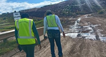 Two workers , a man and a woman in reflective safety clothing, walking towards a landfil site