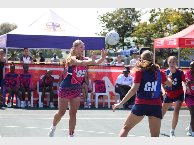 A netball match in action with two players in the frame with a ball between them.