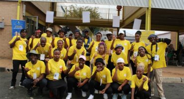 A big group of youth wearing yellow T-shirts standing together.