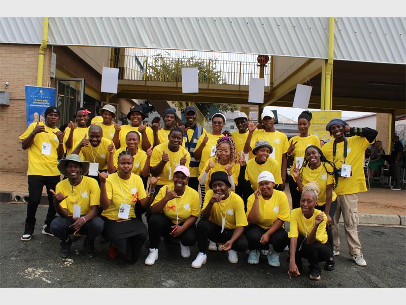 A big group of youth wearing yellow T-shirts standing together.