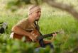 man playing guitar in an overgrown field