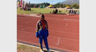 A young black woman standing on the side of an athletic track.