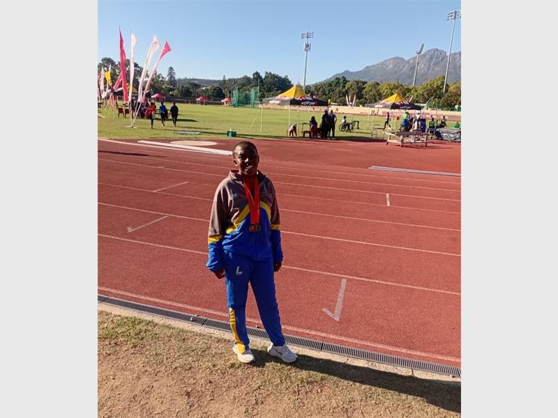 A young black woman standing on the side of an athletic track.