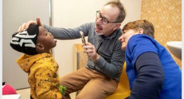 Two doctors examining a small child's mouth using medical instruments.