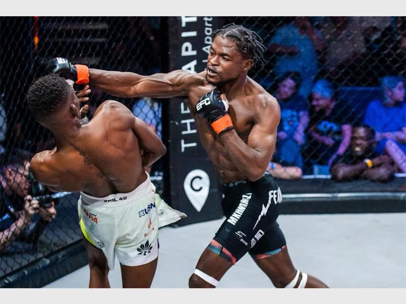 Two black male boxers photographed during a fight as one leans back to avoid a punch.