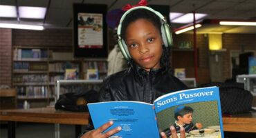 A girl holding a book smiling.