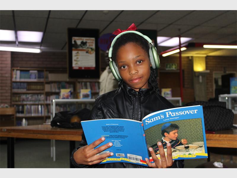 A girl holding a book smiling.