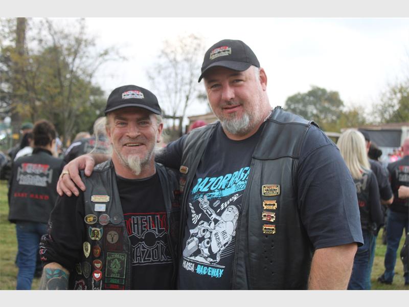 Two male members of the Hell Razors biker club dressed in black wearing their club jackets and black caps.