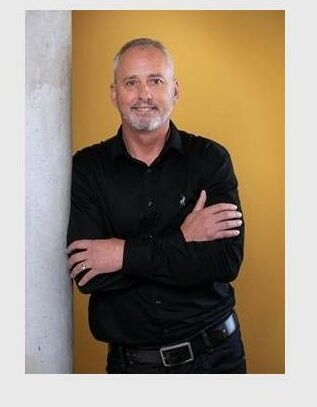 Man wearing a black shirt leaning against a wall