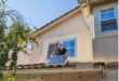 Image of a man standing on a roof holding a solar panel