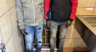 two men pictured with the firearm, knife, magazine and cellphones