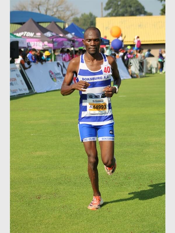 A black male athlete dressed in BAC running kit competing in the Comrades Marathon.