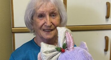 Elderly woman holding a purple stuffed animal