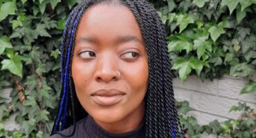 a woman in a black top and cornrow braids