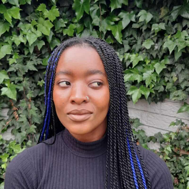 a woman in a black top and cornrow braids