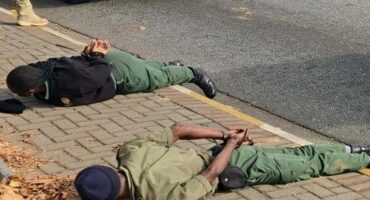 Two uniformed officers laying face down on the pavement