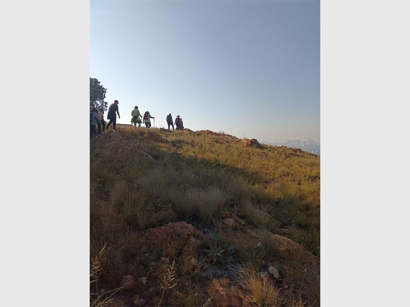 A view of Melville Koppies with a group of hikers against a blue sky.