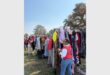 A woman standing next to rails of clothing for the needy at an outreach event.