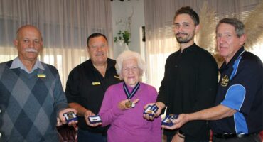 Group of five people, four men and one woman holding medals of honour