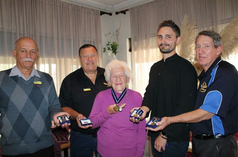 Group of five people, four men and one woman holding medals of honour