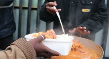 a man serves soup to a needy person