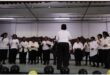 A choir of elderly women dressed in black and white on stage.