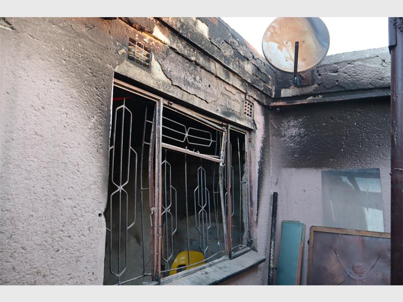 The burnt remains of a home photographed from the outside showing a window frame.