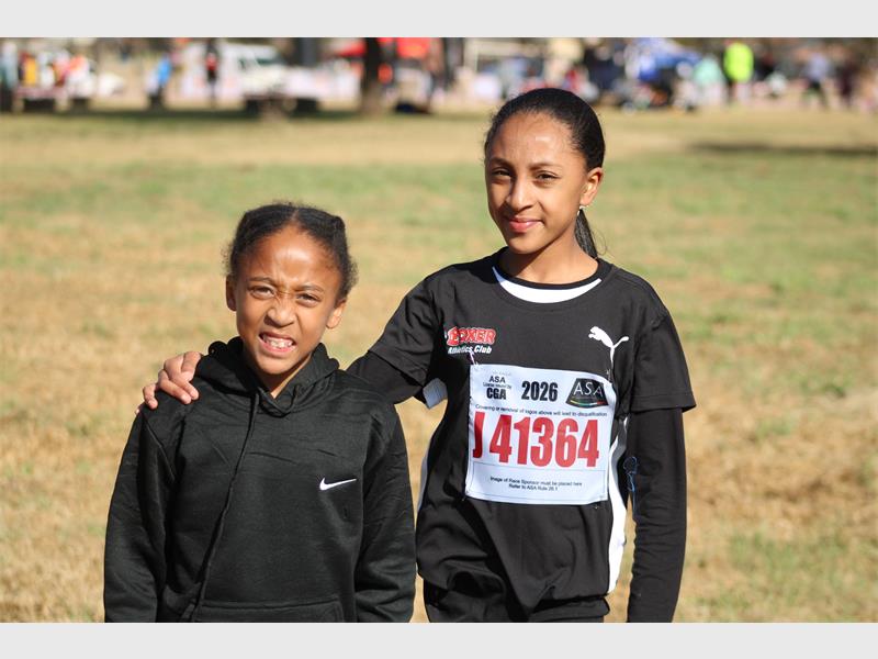 Two young black female athletes one with an arm around the other and both dressed in black kit.